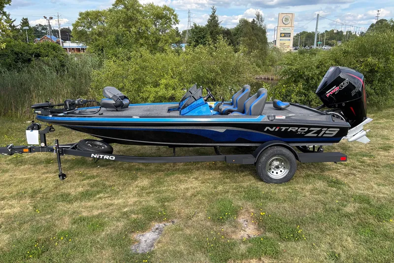 The Image of 2026 Nitro Z19 XL boat on trailer, parked on grassy area with trees in background. - 0