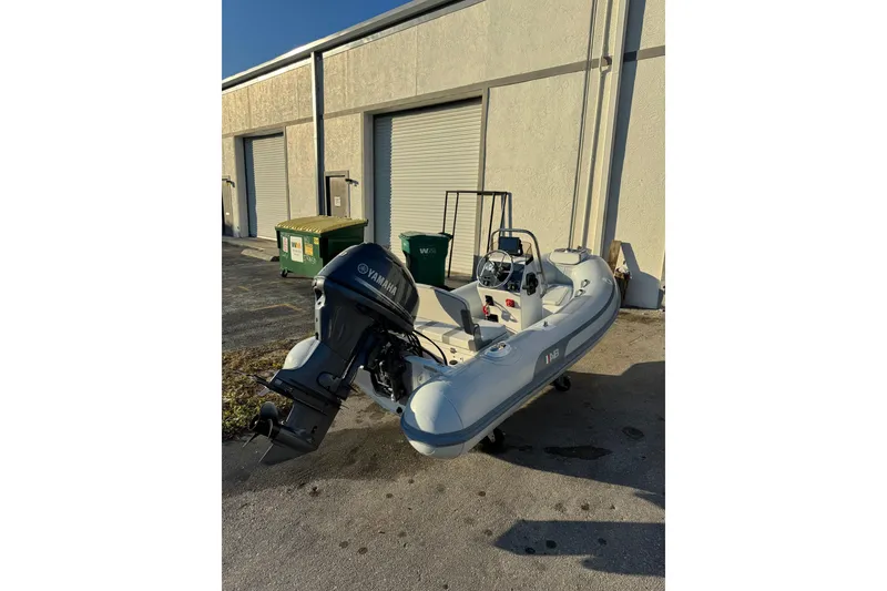 Slide: The Image of 2022 AB Inflatables Alumina 11 ALX boat with Yamaha outboard motor, parked outside a warehouse. - 2