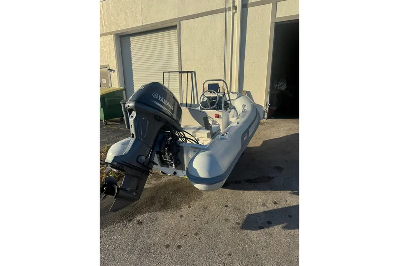 Slide: The Image of 2022 AB Inflatables Alumina 11 ALX boat with Yamaha outboard motor, parked outside a garage. - 4