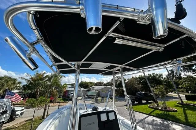 Slide: The Image of 2006 Contender 21 Open boat with T-top and rod holders, parked outdoors. - 12