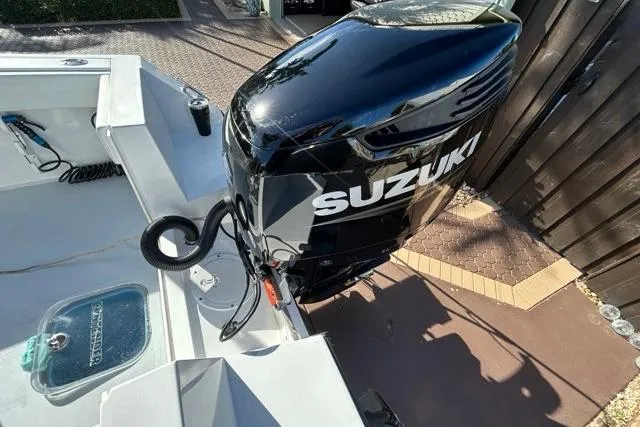 Slide: The Image of 2006 Contender 21 Open boat with Suzuki outboard motor, docked on a sunny day. - 17