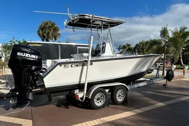Slide: The Image of 2006 Contender 21 Open boat on trailer with Suzuki outboard, parked outdoors. - 26