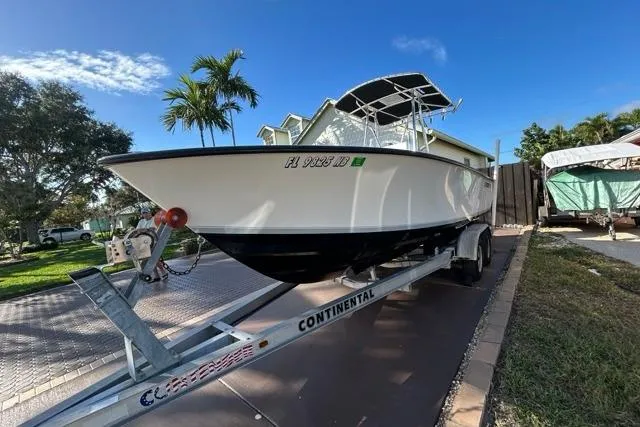 Slide: The Image of 2006 Contender 21 Open boat on trailer, parked in driveway under clear blue sky. - 30