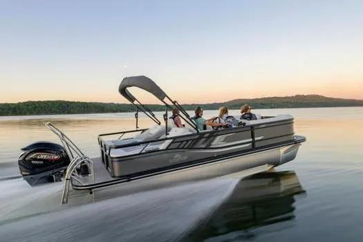 The Image of 2026 SunCatcher Fusion 322SS boat cruising on a serene lake at sunset. - 1