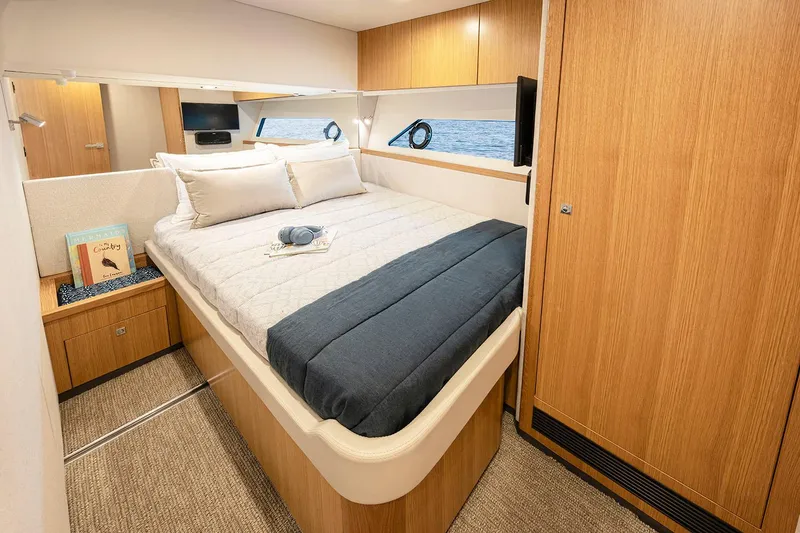 Slide: The Image of Manufacturer Provided Image: Luxurious bedroom interior of 2025 Riviera 585 SUV yacht with modern wood finishes. - 22