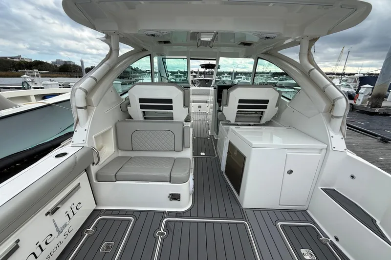 Slide: The Image of 2023 Pursuit DC 326 Dual Console boat interior with seating and storage, docked at marina. - 10