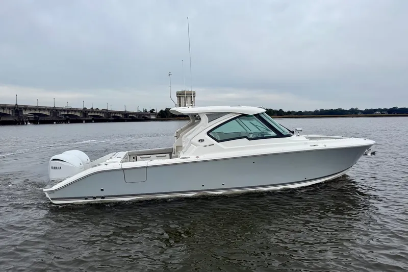 Slide: The Image of 2023 Pursuit DC 326 Dual Console boat on water, side view, overcast sky. - 2
