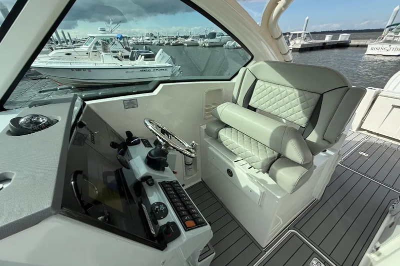 Slide: The Image of 2023 Pursuit DC 326 Dual Console boat interior with helm and seating at marina. - 22