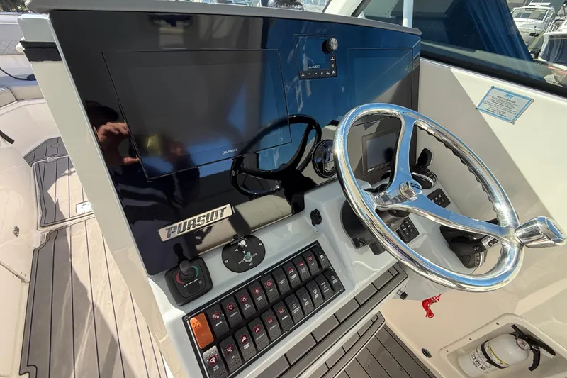 Slide: The Image of 2023 Pursuit DC 326 Dual Console boat dashboard with steering wheel and controls. - 23