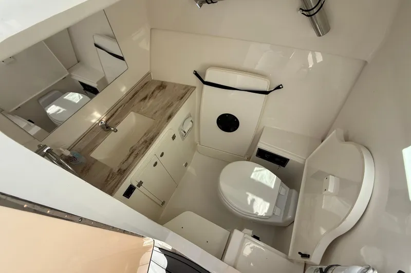 Slide: The Image of 2023 Pursuit DC 326 Dual Console boat bathroom with sink, toilet, and storage cabinets. - 27