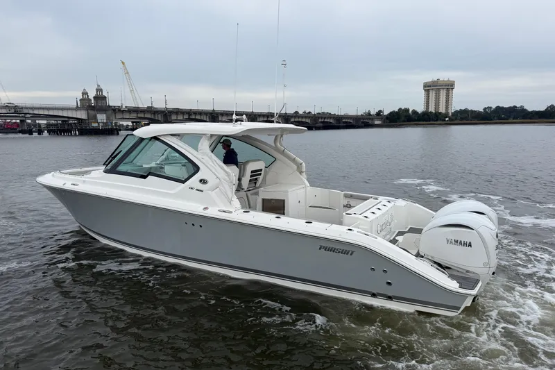 Slide: The Image of 2023 Pursuit DC 326 Dual Console boat cruising on a river with bridge in background. - 3