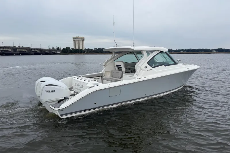 Slide: The Image of 2023 Pursuit DC 326 Dual Console boat cruising on a calm river near a bridge. - 4