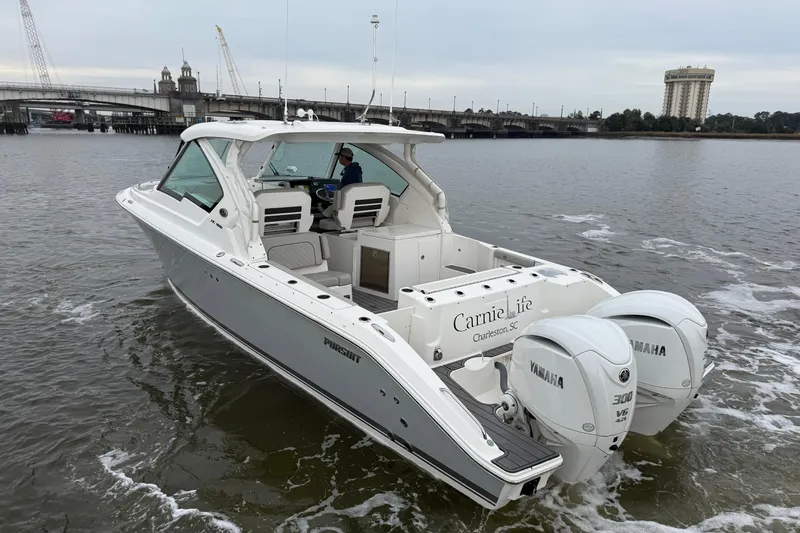 Slide: The Image of 2023 Pursuit DC 326 Dual Console boat cruising on a river near a bridge. - 5