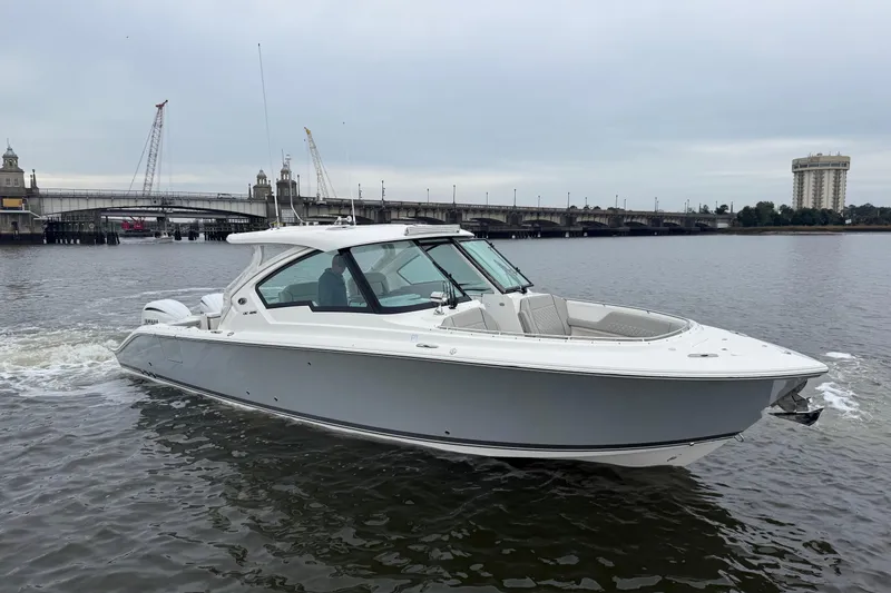 Slide: The Image of 2023 Pursuit DC 326 Dual Console boat cruising on a river near a bridge. - 7