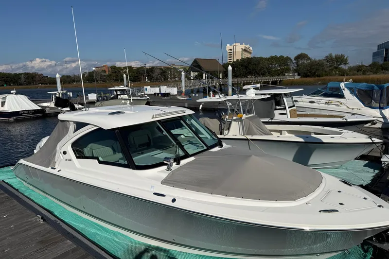 Slide: The Image of 2023 Pursuit DC 326 Dual Console boat docked at marina under clear blue sky. - 9