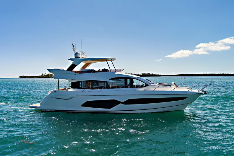 Slide: The Image of 2019 Sunseeker Manhattan 66 yacht cruising on clear blue waters under a sunny sky. - 5