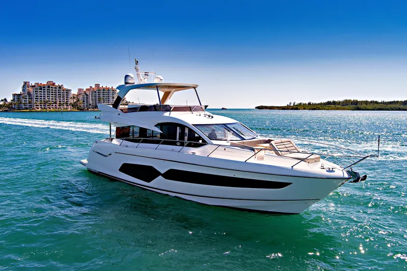 Slide: The Image of 2019 Sunseeker Manhattan 66 yacht cruising on clear blue waters near luxury waterfront buildings. - 6