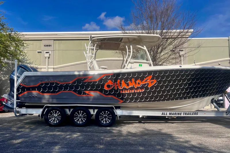 Slide: The Image of 2016 Sailfish 290 CC boat on trailer with custom graphics, parked outdoors. - 3