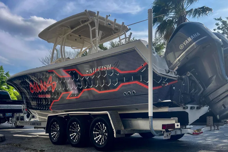 Slide: The Image of 2016 Sailfish 290 CC boat on trailer with Yamaha engines, parked under a cloudy sky. - 4