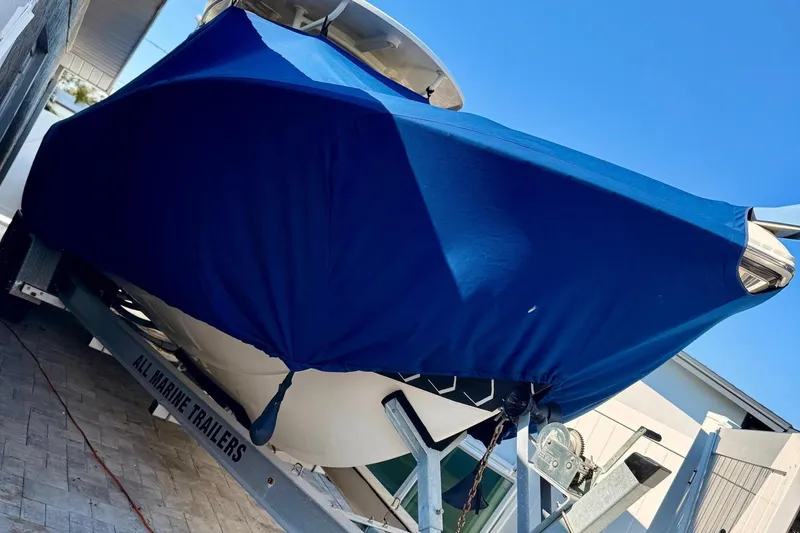 Slide: The Image of 2016 Sailfish 290 CC boat covered on trailer, blue cover, sunny day. - 6
