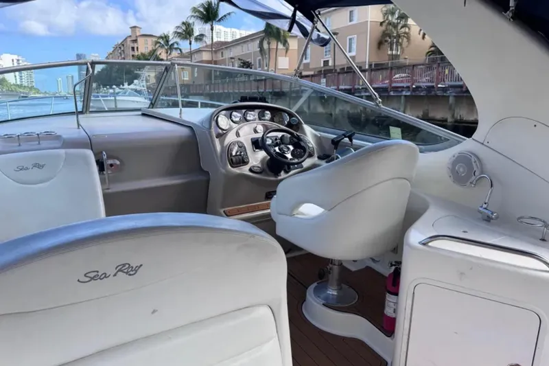 Slide: The Image of 2005 Sea Ray 280 Sundancer boat interior with steering wheel and dashboard, docked by waterfront. - 15