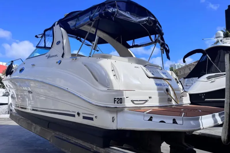 Slide: The Image of 2005 Sea Ray 280 Sundancer boat docked, featuring sleek design and blue canopy. - 2