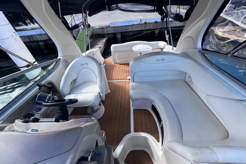 Slide: The Image of 2005 Sea Ray 280 Sundancer interior with white seating and wooden deck. - 7