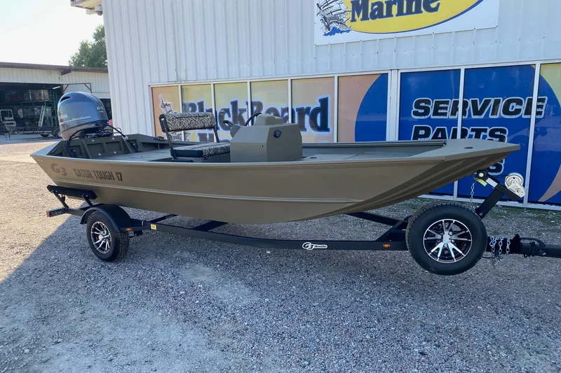 Slide: The Image of 2026 G3 Gator Tough 17 CCJ boat on trailer outside marine service shop. - 1
