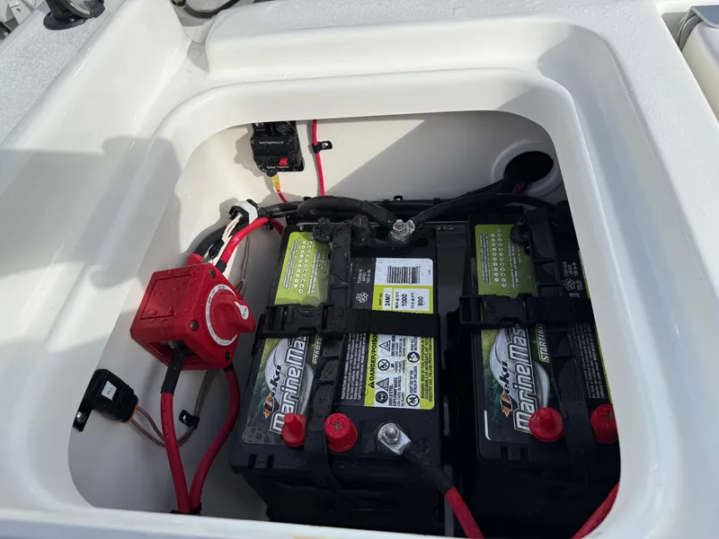 Slide: The Image of 2025 Key West 210 Bay Reef boat battery compartment with dual marine batteries and wiring. - 19