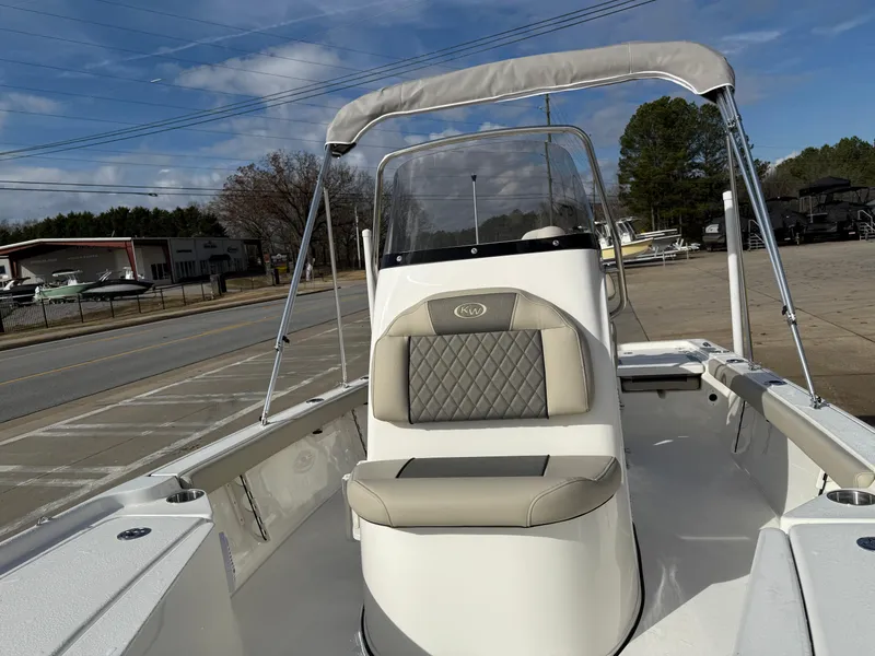 Slide: The Image of 2025 Key West 210 Bay Reef boat with cushioned seating and canopy, parked outdoors. - 9
