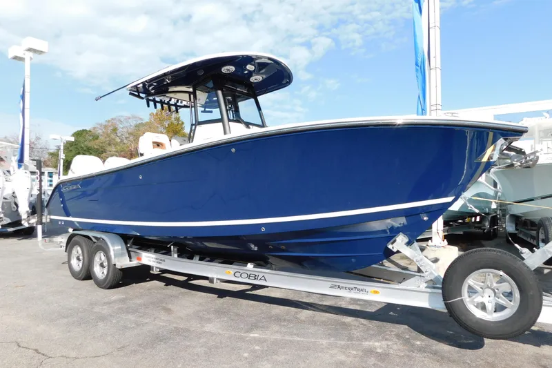Slide: The Image of 2026 Cobia 265 Center Console boat on trailer, blue hull, outdoor display. - 2