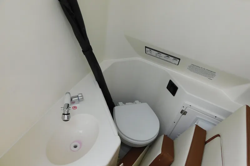 Slide: The Image of 2026 Cobia 265 Center Console boat interior with compact bathroom and sink. - 37