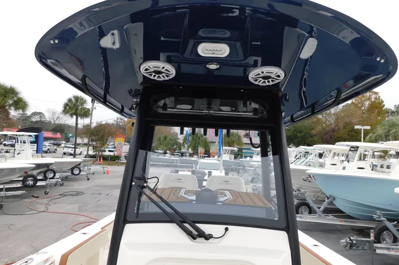 Slide: The Image of 2026 Cobia 265 Center Console boat with T-top and speakers in a marina setting. - 40