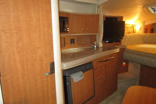 Slide: The Image of 2006 Sea Ray 300 Sundancer interior with kitchenette, cabinets, and cozy sleeping area. - 12