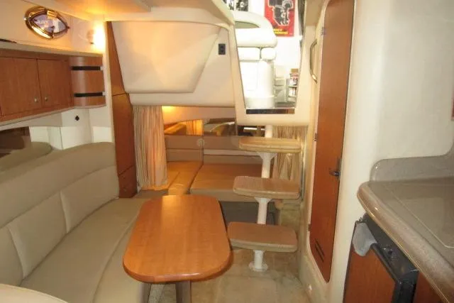 Slide: The Image of Interior of 2006 Sea Ray 300 Sundancer yacht with seating, table, and compact kitchen area. - 19