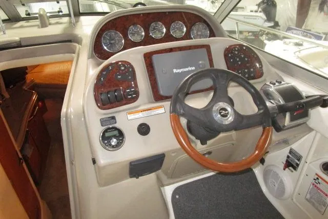 Slide: The Image of 2006 Sea Ray 300 Sundancer helm with Raymarine navigation system and wood-accented steering wheel. - 7
