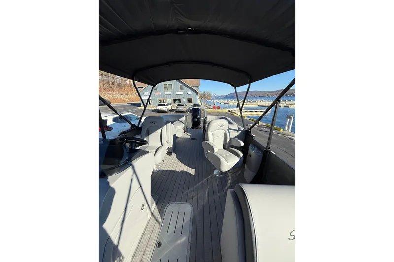 Slide: The Image of 2026 Bentley Pontoons Legacy 223 Navigator interior with seating and helm, docked by the water. - 8