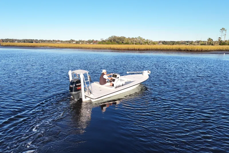 Slide: The Image of 2019 Maverick 18 HPX-V boat cruising on a calm river under a clear blue sky. - 32