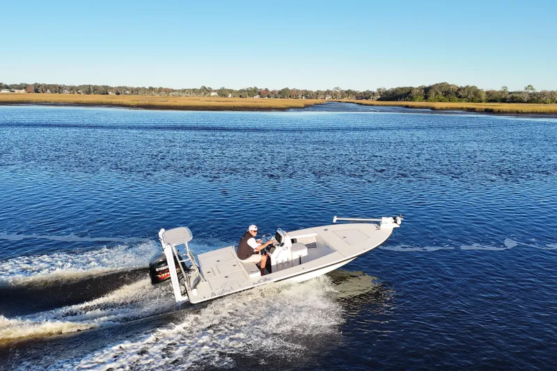 Slide: The Image of 2019 Maverick 18 HPX-V boat cruising on a serene river under clear blue skies. - 52