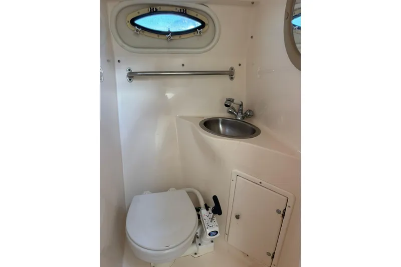 Slide: The Image of 2005 Rinker Fiesta Vee 250 boat bathroom with toilet, sink, and porthole window. - 11