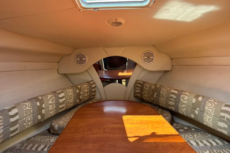 Slide: The Image of 2005 Rinker Fiesta Vee 250 cabin interior with patterned seating and wooden table. - 16