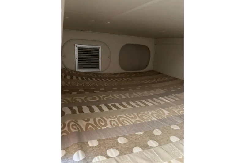 Slide: The Image of 2005 Rinker Fiesta Vee 250 cabin interior with patterned bedding and ventilation. - 17