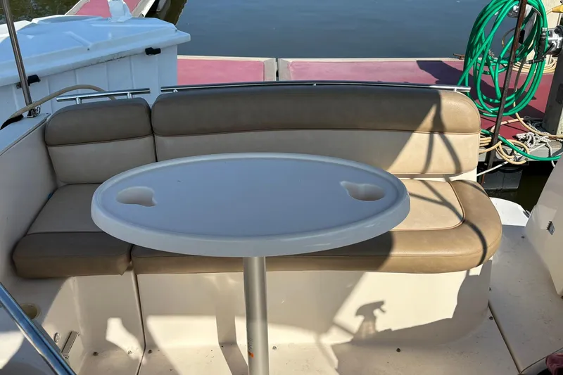 Slide: The Image of 2005 Rinker Fiesta Vee 250 boat interior with cushioned seating and oval table. - 7