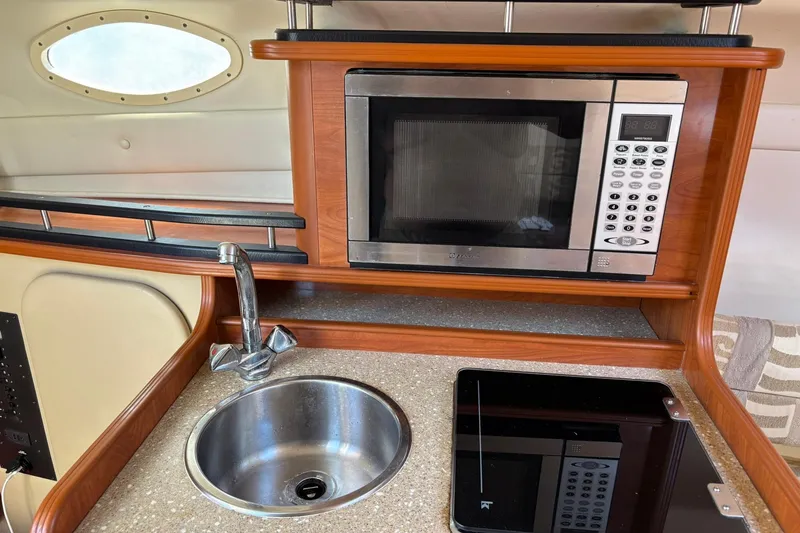 Slide: The Image of 2005 Rinker Fiesta Vee 250 boat kitchen with microwave, sink, and countertop. - 9