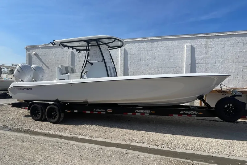 The Image of 2026 Contender 29 Bay boat on trailer, parked outdoors under clear blue sky. - 1