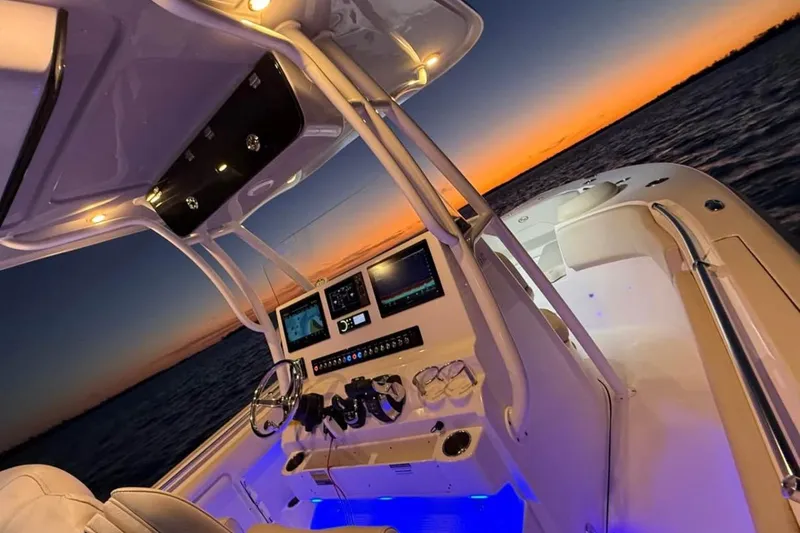 Slide: The Image of 2022 Key West 263 FS boat interior at sunset, featuring illuminated dashboard and ocean view. - 12