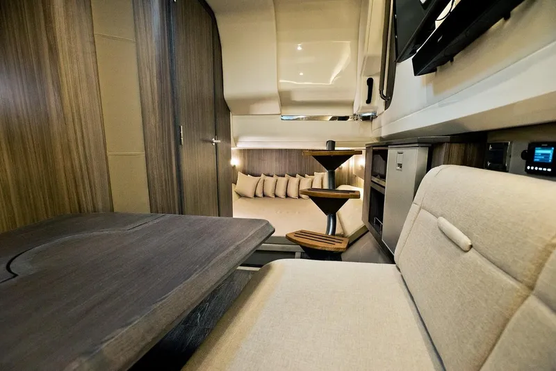 Slide: The Image of Luxury seating area on 2021 Sea Ray SLX 400 boat with wooden table and cushioned seats. - 18