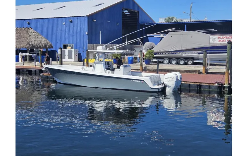 Slide: The Image of 2019 Contender 35 ST boat docked at marina with blue building backdrop. - 1