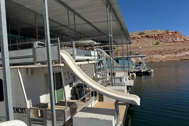 Slide: The Image of Houseboat with slide on calm water, Myacht 4815, 2001 model, docked near rocky shoreline. - 10