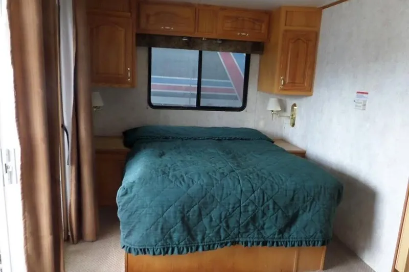 Slide: The Image of Cozy bedroom interior of 2001 Myacht 4815 with green bedding and wooden cabinets. - 6